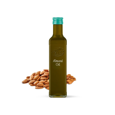 A pile of raw almonds beside a bottle of almond oil.