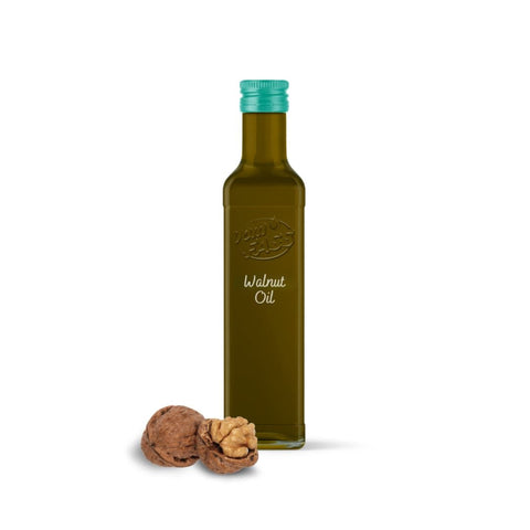 Walnut oil in a dark glass bottle with a green cap, displayed next to whole and cracked walnuts.