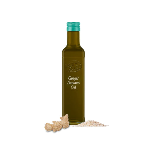 Sesame oil infused with ginger in a tinted glass bottle with a green cap, displayed alongside fresh ginger and sesame seeds.
