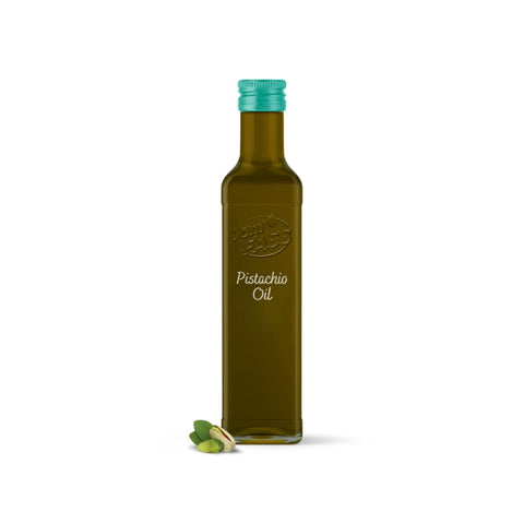 Pistachio oil in a dark glass bottle with a teal cap, labeled on the front, placed beside a few shelled pistachios.