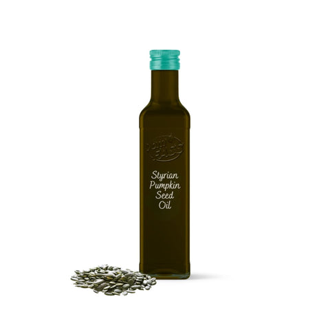 Pumpkin seed oil in a dark glass bottle with a green cap, accompanied by a small pile of pumpkin seeds.