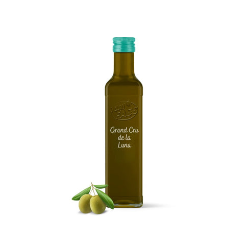 Grand Cru de la Luna extra virgin olive oil in a glass bottle with a teal cap, accompanied by fresh green olives.